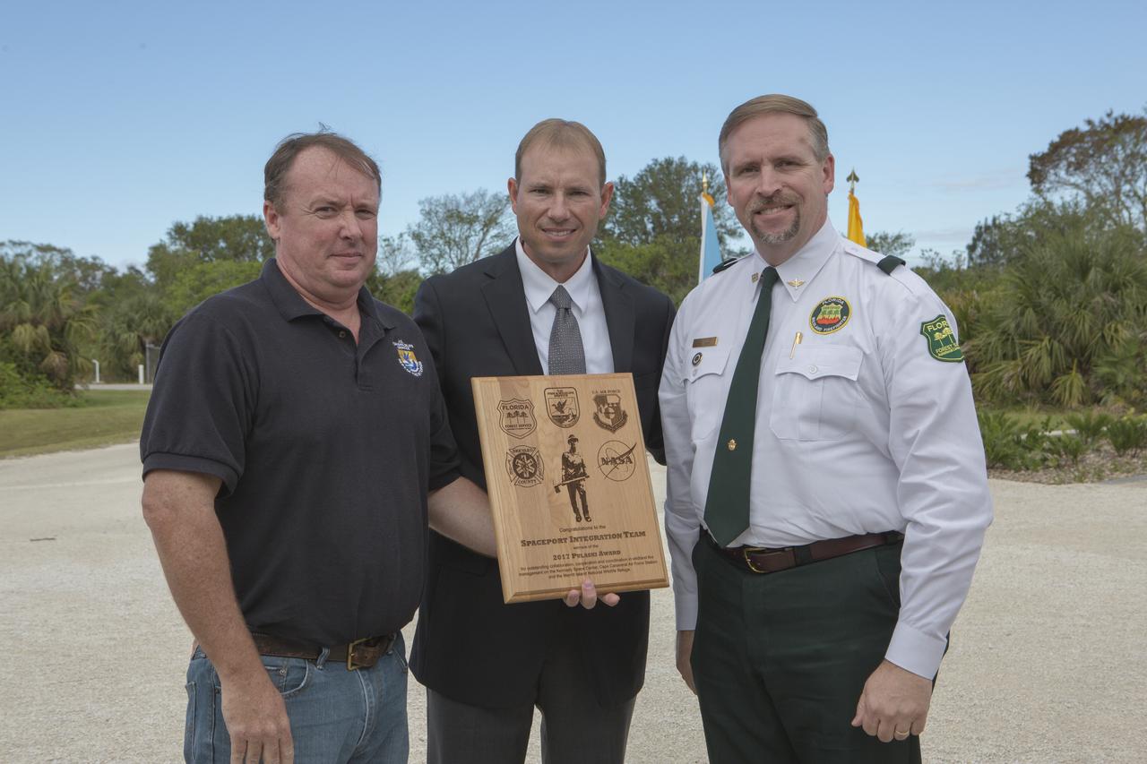 From left, Jon Wallace, deputy fire coordinator, U.S. Fish and Wildlife Service Southeast Region, Atlanta, Georgia; Chris Wilcox, U.S. Fish and Wildlife chief, Fire Management, National Interagency Fire Center, Boise, Idaho; and John Fish, chief, Florida Forest Service, pose for a portrait following a ceremony Nov. 1 on the Merritt Island National Wildlife Refuge in Florida. During the joint ceremony, the Spaceport Integration Team and its partners were presented with the prestigious 2017 Pulaski Award and a new memorial marker was dedicated. The multi-agency team includes representatives from NASA's Kennedy Space Center, Cape Canaveral Air Force Station's 45th Space Wing, the Merritt Island National Wildlife Refuge, as well as the Florida Forest Service and Brevard County Fire Rescue. The memorial marker honors two fallen firefighters, Scott Maness and Beau Sauselein, who died fighting a wildfire on space center property in 1981. Held outdoors, the ceremony was attended by 140 guests.