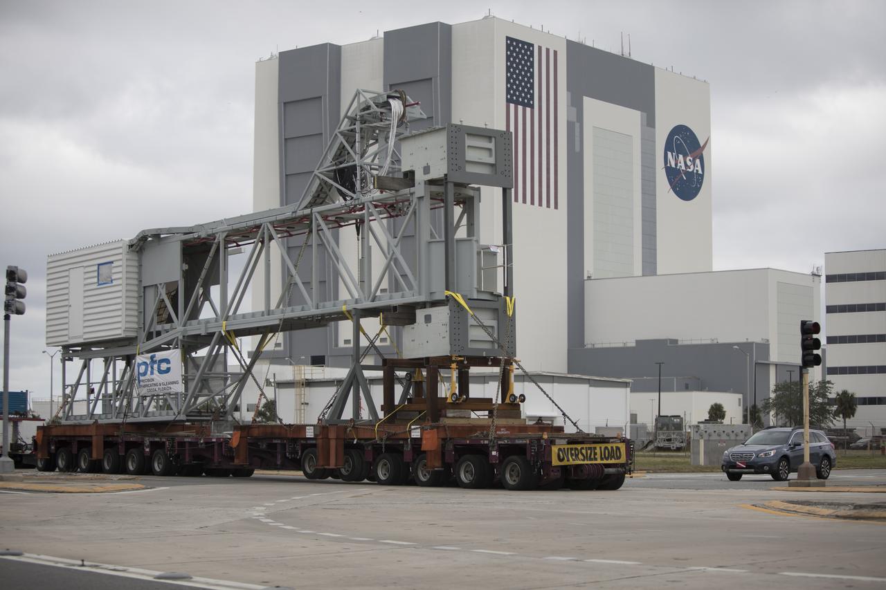 A heavy-load transport truck carrying the Orion crew access arm passes the Vehicle Assembly Building on its way to the mobile launcher at NASA's Kennedy Space Center in Florida. The access arm will be installed at about the 274-foot level on the mobile launcher tower. It will rotate from its retracted position and interface with the Orion crew hatch location to provide entry to the Orion crew module. The Ground Systems Development and Operations Program is overseeing installation of umbilicals and launch accessories on the ML tower to prepare for Exploration Mission-1.