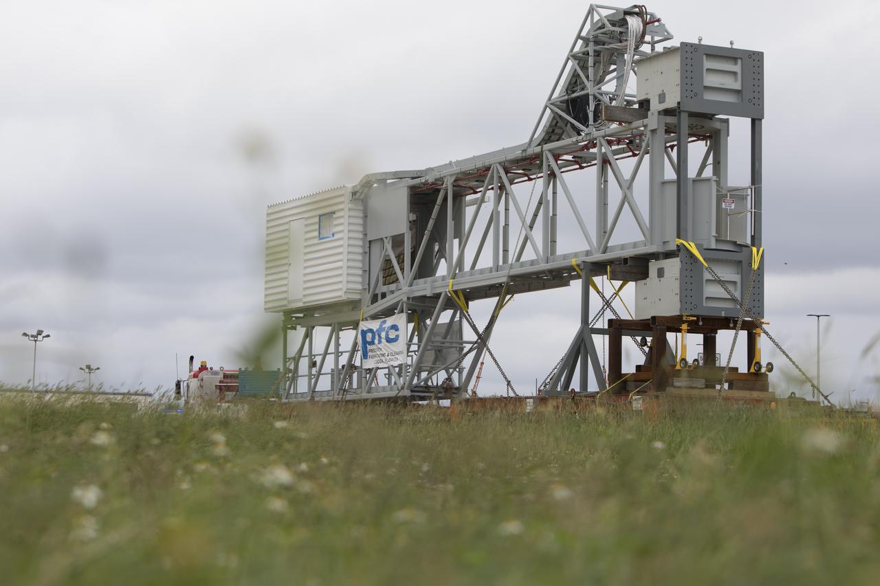 A heavy-load transport truck carrying the Orion crew access arm makes its way toward the mobile launcher (ML) at NASA's Kennedy Space Center in Florida. The crew access arm will be installed at about the 274-foot level on the mobile launcher tower. It will rotate from its retracted position and interface with the Orion crew hatch location to provide entry to the Orion crew module. The Ground Systems Development and Operations Program is overseeing installation of umbilicals and launch accessories on the ML tower to prepare for Exploration Mission-1. 