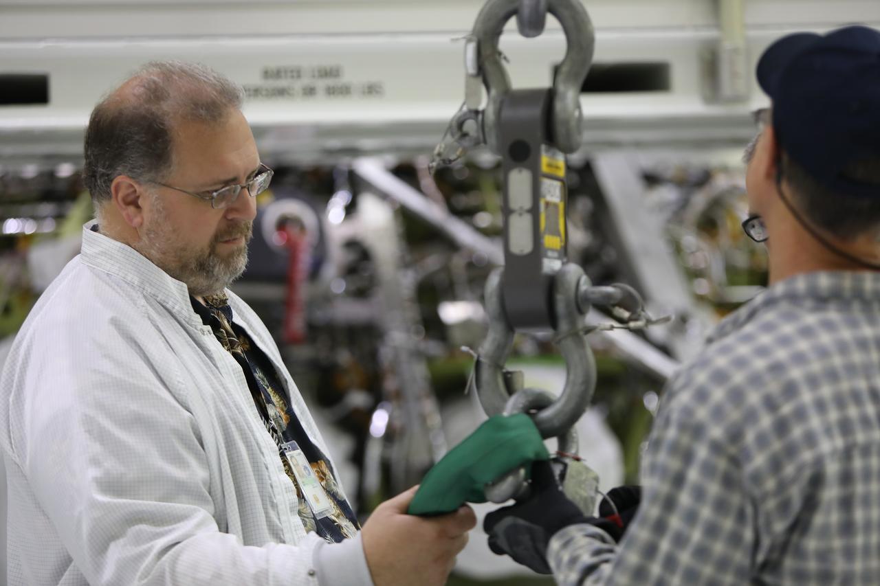 Technicians check a crane that will be used during move operations of the Orion crew module for Exploration Mission-1 to the thermal chamber in the Neil Armstrong Operations and Checkout Building high bay at NASA's Kennedy Space Center in Florida. The crew module will undergo a thermal cycle test to assess the workmanship of critical hardware and structural locations. The test also demonstrates crew module subsystem operations in a thermally stressing environment to confirm no damage or anomalous hardware conditions as a result of the test. The Orion spacecraft will launch atop NASA's Space Launch System rocket on its first uncrewed integrated flight.
