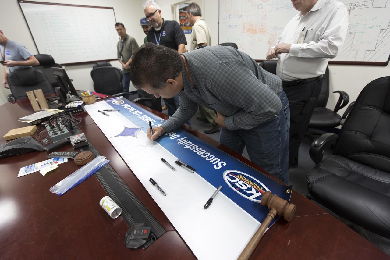 Workers sign the banner marking the successful delivery of a liquid oxygen test tank, called Tardis, in the Prototype Development Laboratory at NASA's Kennedy Space Center in Florida. Engineers and technicians worked together to develop the tank and build it at the lab to support cryogenic testing at Johnson Space Center's White Sands Test Facility in Las Cruces, New Mexico. The 12-foot-tall, 3,810-pound aluminum tank will be shipped to White Sands for testing.
