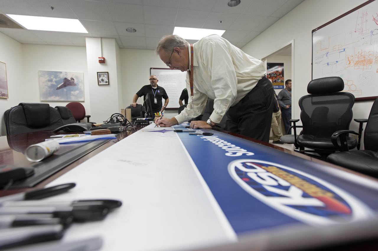 NASA Kennedy Space Center's Engineering Director Pat Simpkins signs the banner marking the successful delivery of a liquid oxygen test tank, called Tardis, in the Prototype Development Laboratory at NASA's Kennedy Space Center in Florida. Engineers and technicians worked together to develop the tank and build it to support cryogenic testing at Johnson Space Center's White Stands Test Facility in Las Cruces, New Mexico. The 12-foot-tall, 3,810-pound aluminum tank will be shipped to White Sands for testing.