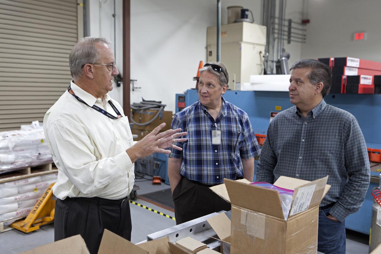 NASA Kennedy Space Center's Engineering Director Pat Simpkins, at left, talks with Michael E. Johnson, a project engineer; and Emilio Cruz, deputy division chief in the Laboratories, Development and Testing Division, inside the Prototype Development Laboratory. A banner signing event was held to mark the successful delivery of a liquid oxygen test tank, called Tardis. Engineers and technicians worked together to develop the tank and build it at the lab to support cryogenic testing at Johnson Space Center's White Sands Test Facility in Las Cruces, New Mexico. The 12-foot-tall, 3,810-pound aluminum tank will be shipped to White Sands for testing. 