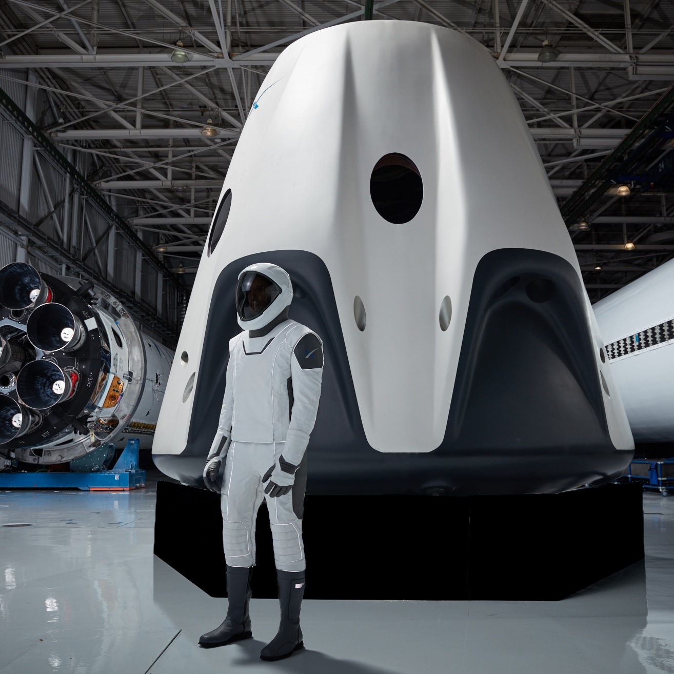 The SpaceX spacesuit that will be worn by astronauts aboard its Crew Dragon spacecraft (in the background) during missions to and from the International Space Station.