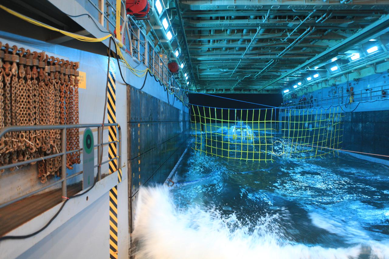 A test article of Orion floats in 6-feet of water in the well deck of the USS Anchorage. The NASA Recovery Team from Kennedy Space Center is working with the U.S. Navy to improve recovery procedures and hardware ahead of Orion’s next flight, Exploration Mission-1, when it splashes down in the Pacific Ocean.