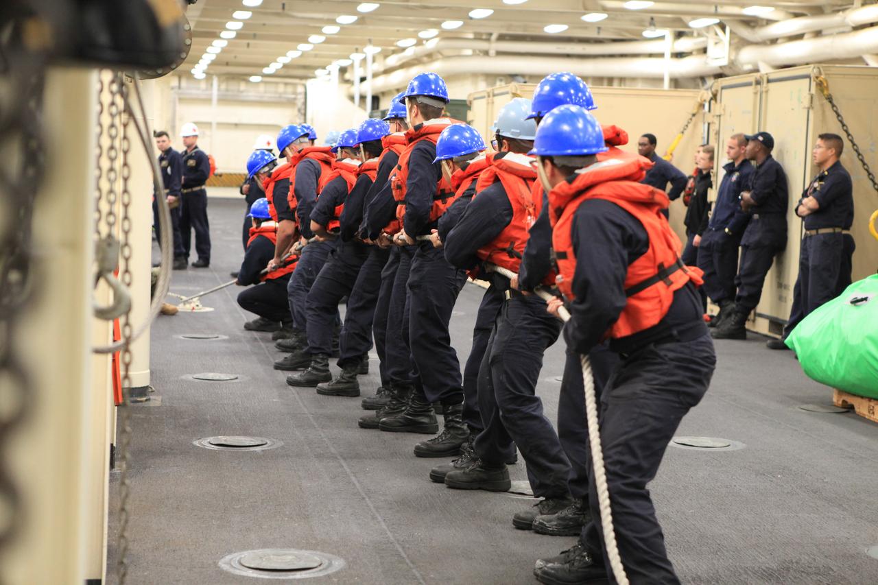 USS Anchorage’s Deck Department is heaving around the line as they bring up “Oscar,” a dummy used for man overboard drills. During Underway Recovery Test 6, the USS Anchorage’s man overboard drill gave Kennedy Space Center’s NASA Recovery Team a glimpse of one way an astronaut could be brought from a small boat onto the ship using a stretcher. Once the Orion capsule splashes down in the Pacific Ocean, astronauts can choose to stay in the capsule until it is pulled into the well deck of the Navy vessel, or have a diver retrieve them first and then get the capsule later.