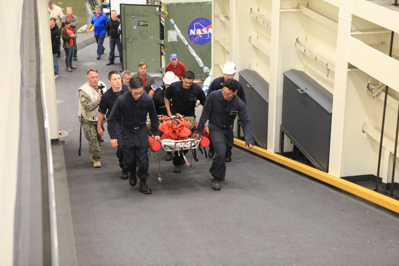 Sailors from the USS Anchorage simulate “Oscar,” a dummy used for man overboard drills, to the medical unit. During Underway Recovery Test 6, the USS Anchorage’s man overboard drill gave Kennedy Space Center’s NASA Recovery Team a glimpse of one way an astronaut could be brought from a small boat onto the ship using a stretcher. Once the Orion capsule splashes down in the Pacific Ocean, astronauts can choose to stay in the capsule until it is pulled into the well deck of the Navy vessel, or have a diver retrieve them in the open water and then get the capsule later.