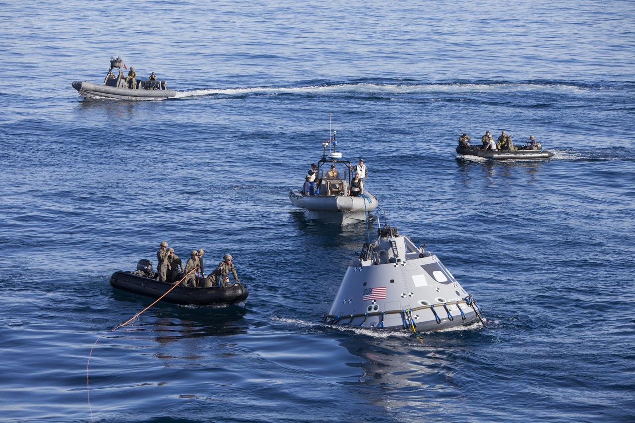 Teams from the U.S. Navy’s Explosive Ordnance Disposal Mobile Unit 3, the Special Boat Unit, the USS Anchorage and the USS New Orleans work together to connect tending lines to the Orion test article off the coast of San Diego. Kennedy Space Center’s NASA Recovery Team works with the U.S. Navy to improve recovery procedures and hardware ahead of Orion's next flight, Exploration Mission-1, when it splashes down in the Pacific Ocean.