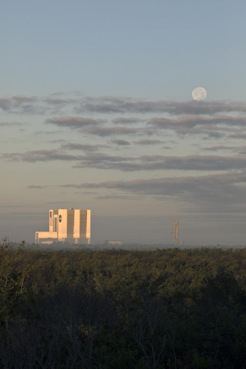 A full Moon sets behind the Vehicle Assembly Building and Mobile Launcher at NASA’s Kennedy Space Center in Florida. At the nation’s premier multi-user spaceport, NASA and its commercial and international partners are looking to return humans to the Moon and beyond utilizing a variety of rockets and capabilities.