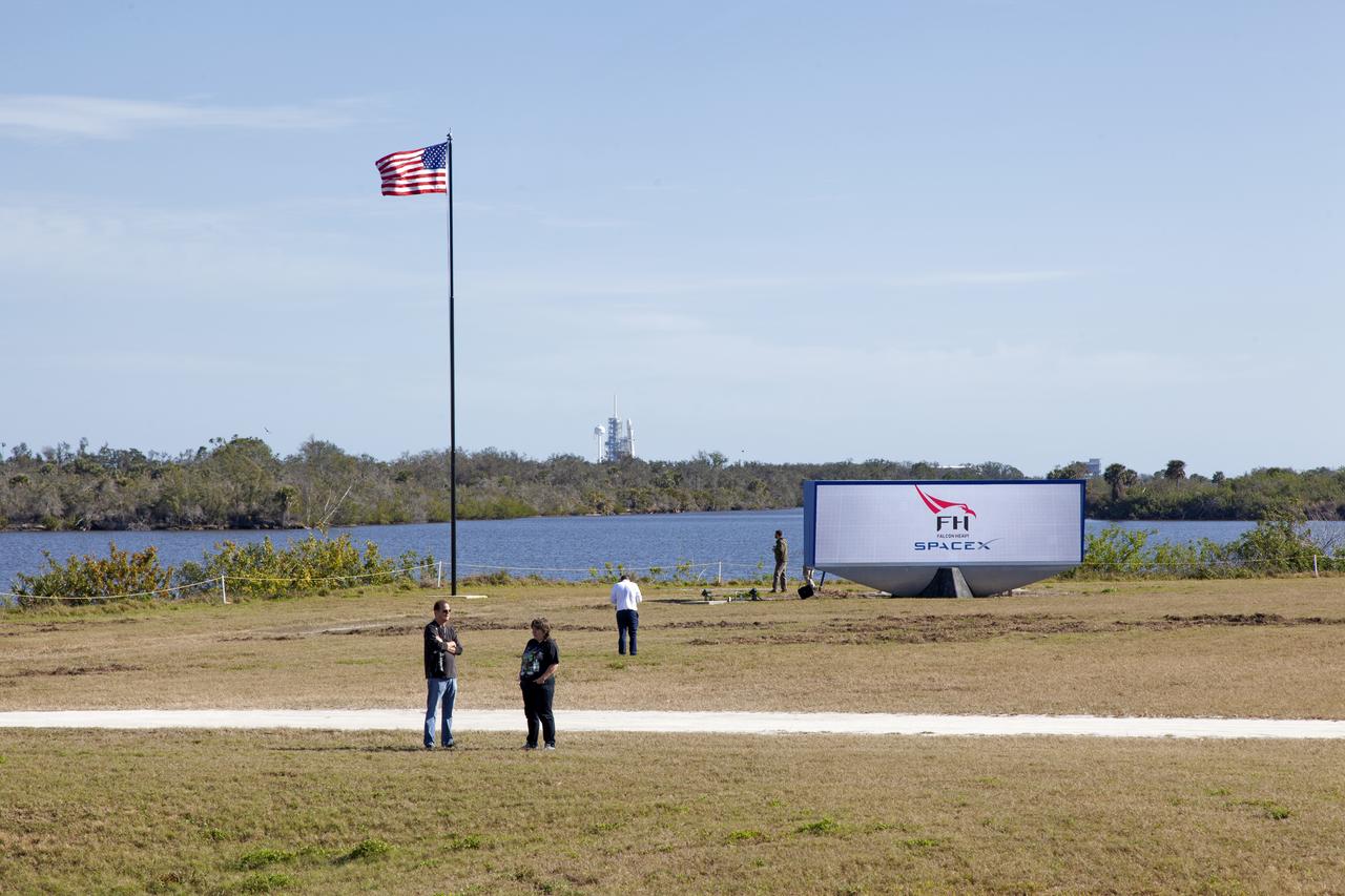 Members of the news media begin to gather near the countdown clock at NASA’s Kennedy Space Center in Florida to await liftoff of the SpaceX Falcon Heavy rocket, seen in the background at Launch Complex 39A. The demonstration flight will be a significant milestone for the world's premier multi-user spaceport. In 2014, NASA signed a property agreement with SpaceX for the use and operation of the center's pad 39A, where the company has launched Falcon 9 rockets and is preparing for the first Falcon Heavy. NASA also has Space Act Agreements in place with partners, such as SpaceX, to provide services needed to process and launch rockets and spacecraft.