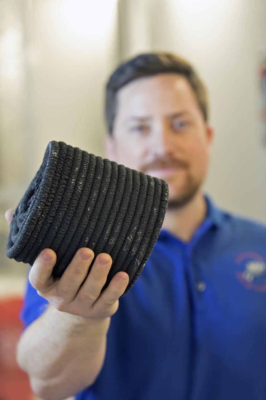 Nathan Gelino, a NASA research engineer at Kennedy Space Center in Florida displays a 3-D printed cylinder used for compression testing. Engineers at the center’s Swamp Works measured how much force it takes to break the structure before moving on to 3-D printing with a simulated lunar regolith, or dirt, and polymers. Next, Gelino and his group are working on a Zero Launch Mass 3-D printer that can be used for construction projects on the Moon and Mars, even for troops in remote locations here on Earth. Zero launch mass refers to the fact that the printer uses these pellets to prove that space explorers can use resources at their destination instead of taking everything with them, saving them launch mass and money. Gelino and his team are working with Marshall Space Flight Center in Huntsville, Alabama, and the U.S. Army Corps of Engineers to develop a system that can 3-D print barracks in remote locations on Earth, using the resources they have where they are.