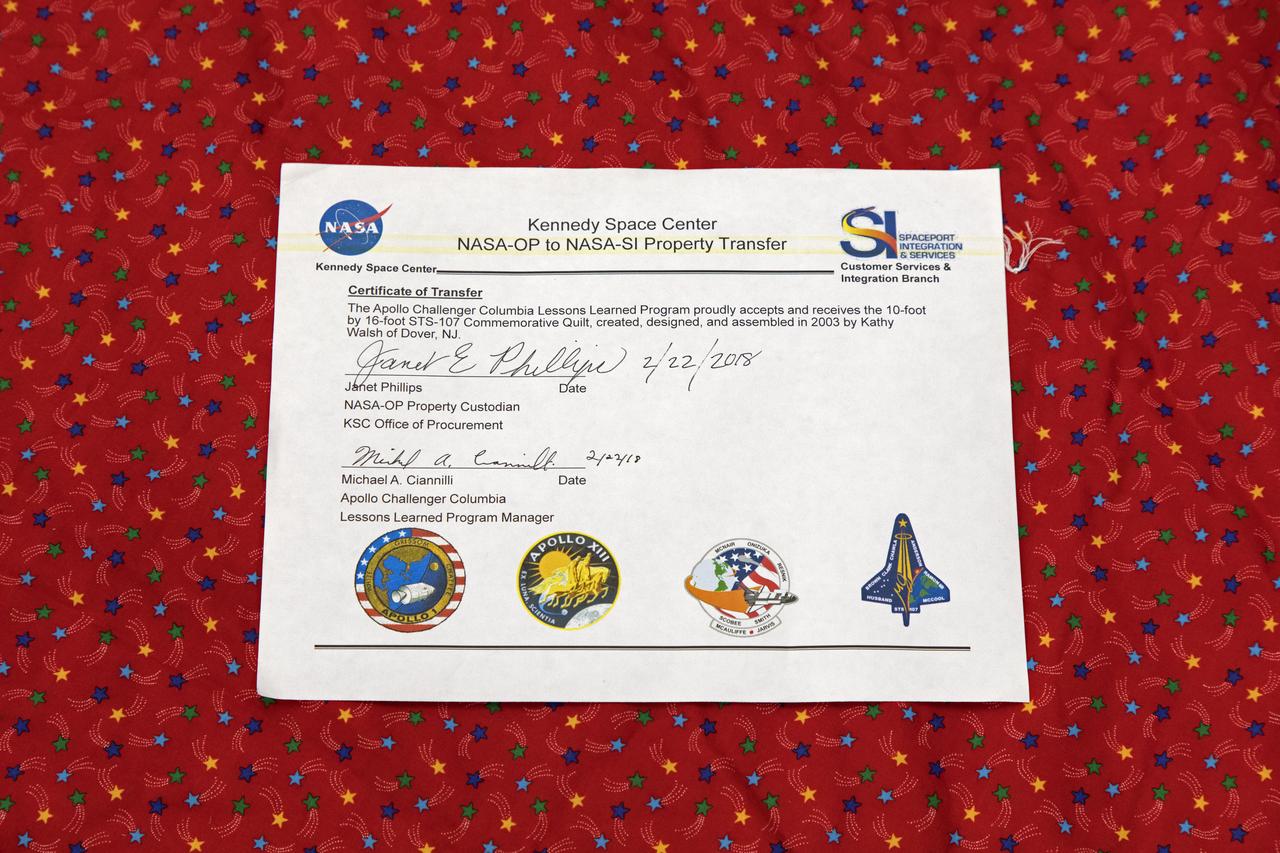 A certificate is on display that confirms the transfer of a giant hand-made quilt in honor of space shuttle Columbia and her crew from the Office of Procurement to the Columbia Preservation Room inside the Vehicle Assembly Building at NASA's Kennedy Space Center in Florida. The quilt was made by Katherine Walsh, a lifelong NASA and space program fan originally from Kentucky. The quilt will be displayed with its certificate in the preservation room as part of NASA's Apollo, Challenger, Columbia Lessons Learned Program. 
