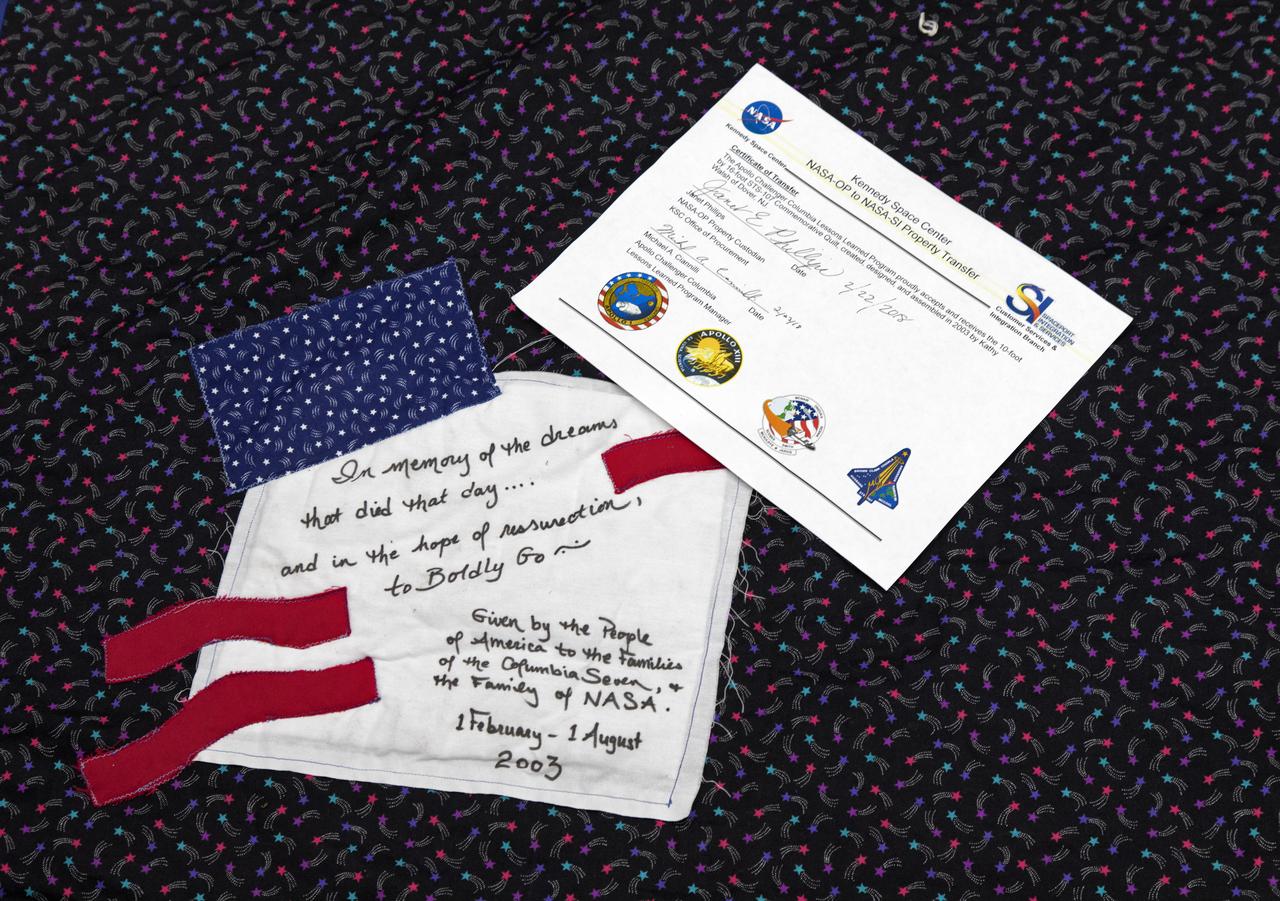 A certificate and quilt square are on display that confirms the transfer of a giant hand-made quilt in honor of space shuttle Columbia and her crew from the Office of Procurement to the Columbia Preservation Room inside the Vehicle Assembly Building at NASA's Kennedy Space Center in Florida. The quilt was made by Katherine Walsh, a lifelong NASA and space program fan originally from Kentucky. The quilt will be displayed in the preservation room with its certificate as part of NASA's Apollo, Challenger, Columbia Lessons Learned Program.