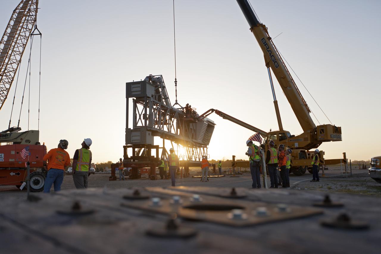 At NASA's Kennedy Space Center in Florida, a crane is prepared to lift the Orion crew access arm (CAA) so it can be attached to the mobile launcher (ML). The arm will be installed at about the 274-foot level on the ML tower. NASA's Exploration Ground Systems organization has been overseeing installation of umbilicals and other launch accessories on the 380-foot-tall ML in preparation for stacking the first launch of the Space launch System, or SLS, rocket with an Orion spacecraft. The CAA is designed to rotate from its retracted position and line up with Orion's crew hatch providing entry for astronauts and technicians.