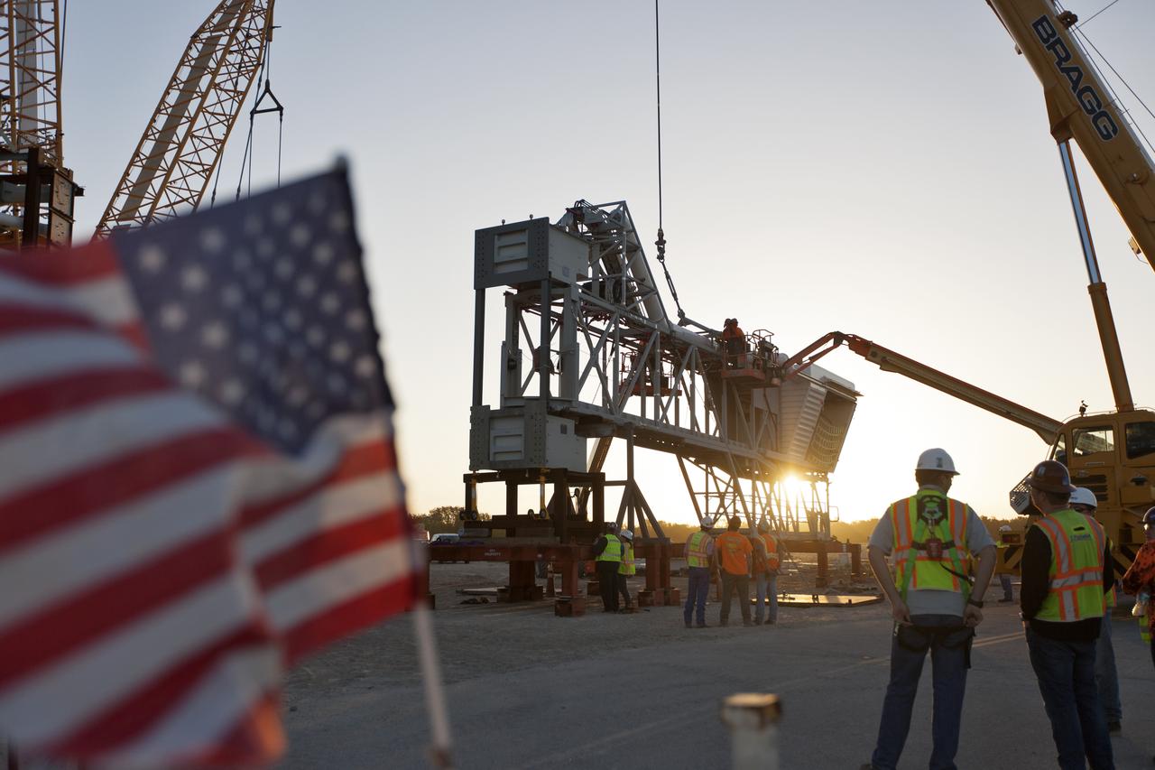 Under the watchful eye of technicians and engineers, a crane is prepared to lift the Orion crew access arm (CAA) so it can be attached to the mobile launcher (ML) at NASA's Kennedy Space Center in Florida. The arm will be installed at about the 274-foot level on the ML tower. NASA's Exploration Ground Systems organization has been overseeing installation of umbilicals and other launch accessories on the 380-foot-tall ML in preparation for stacking the first launch of the Space launch System, or SLS, rocket with an Orion spacecraft. The CAA is designed to rotate from its retracted position and line up with Orion's crew hatch providing entry for astronauts and technicians.