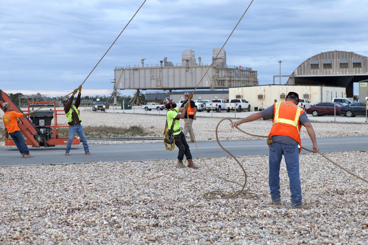 At NASA's Kennedy Space Center in Florida, technicians assist as a crane lifts the Orion crew access arm (CAA) so it can be attached to the mobile launcher (ML). The arm will be installed at about the 274-foot level on the ML tower. NASA's Exploration Ground Systems organization has been overseeing installation of umbilicals and other launch accessories on the 380-foot-tall ML in preparation for stacking the first launch of the Space launch System (SLS), rocket with an Orion spacecraft. The CAA is designed to rotate from its retracted position and line up with Orion's crew hatch providing entry for astronauts and technicians.