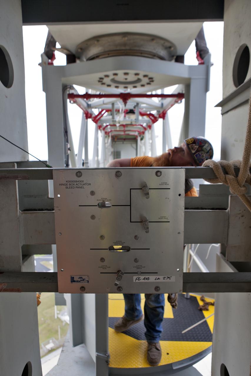 With a control panel visible in the foreground, a technician begins installation of the Orion crew access arm (CAA) to the mobile launcher (ML) tower at NASA's Kennedy Space Center in Florida. NASA's Exploration Ground Systems organization has been overseeing installation of umbilicals and other launch accessories on the 380-foot-tall ML in preparation for stacking the first launch of the Space launch System, or SLS, rocket with an Orion spacecraft. The CAA is designed to rotate from its retracted position and line up with Orion's crew hatch providing entry for astronauts and technicians.