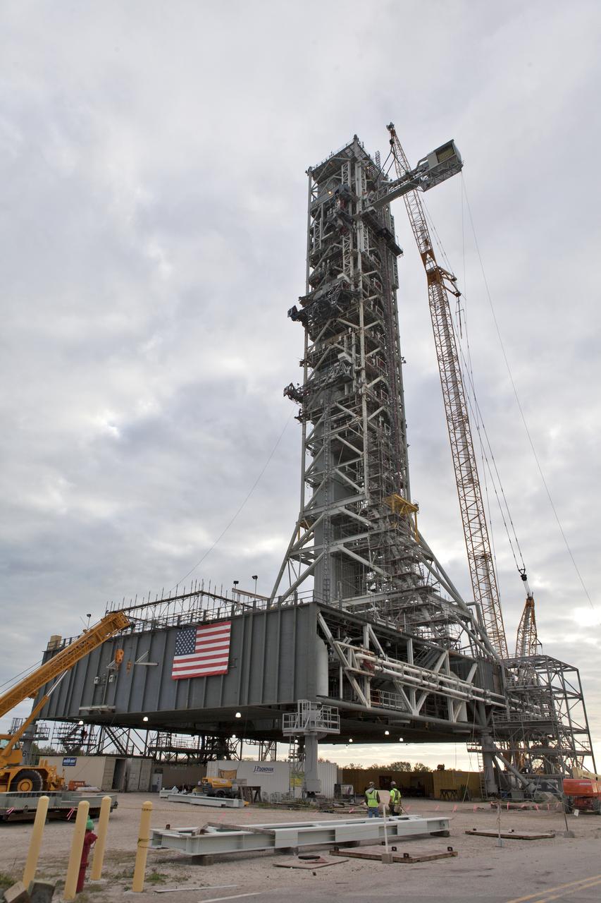 At NASA's Kennedy Space Center in Florida, a crane positions the Orion crew access arm (CAA) so it can be attached to the mobile launcher (ML). The arm will be installed at about the 274-foot level on the ML tower. NASA's Exploration Ground Systems organization has been overseeing installation of umbilicals and other launch accessories on the 380-foot-tall ML in preparation for stacking the first launch of the Space launch System (SLS), rocket with an Orion spacecraft. The CAA is designed to rotate from its retracted position and line up with Orion's crew hatch providing entry for astronauts and technicians.