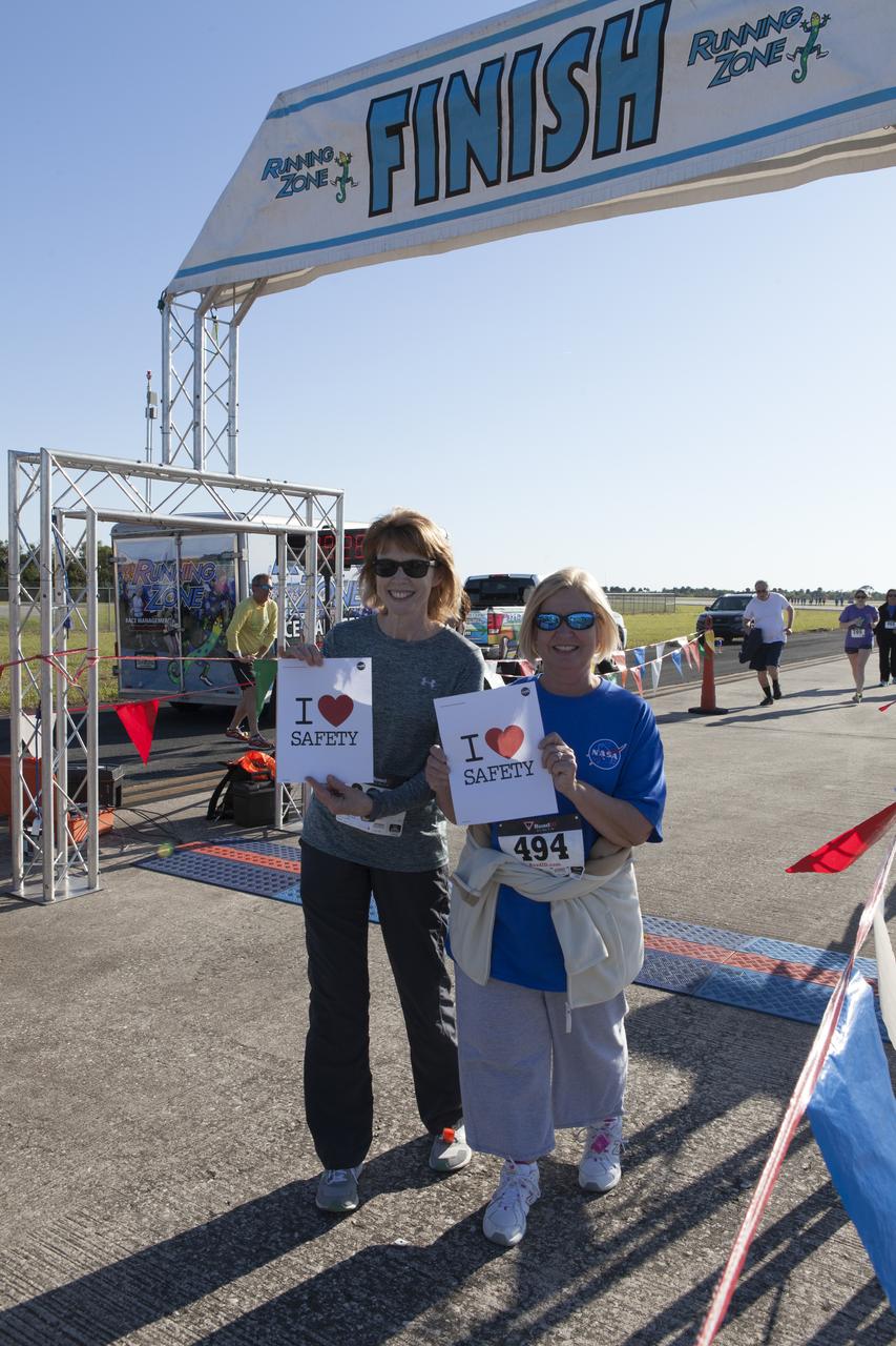 Kennedy Space Center employees hold up signs showing their commitment to safety after crossing the finish line at the KSC Walk Run. The annual event, part of Kennedy’s Safety and Health Days, offers 10K, 5K and 2-mile options on the Shuttle Landing Facility runway in the spirit of friendly competition.
