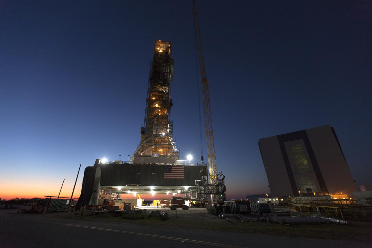 The mobile launcher (ML) tower is lit up before early morning sunrise at NASA's Kennedy Space Center in Florida. Preparations are underway to lift and install the Interim Cryogenic Propulsion Stage Umbilical (ICPSU) at about the 240-foot-level on the tower. The last of the large umbilicals to be installed, the ICPSU will provide super-cooled hydrogen and liquid oxygen to the Space Launch System (SLS) rocket's interim cryogenic propulsion stage, or upper stage, at T-0 for Exploration Mission-1. The umbilical will supply fuel, oxidizer, gaseous helium, hazardous gas leak detection, electrical commodities and environment control systems to the upper stage of the SLS rocket during launch. Exploration Ground Systems is overseeing installation of the umbilicals on the ML. 