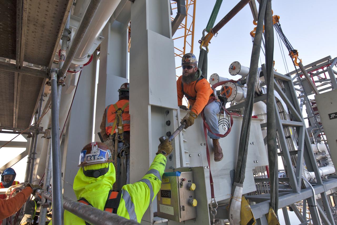 Construction workers with JP Donovan install the Interim Cryogenic Propulsion Stage Umbilical (ICPSU) at about the 240-foot-level of the mobile launcher (ML) tower at NASA's Kennedy Space Center in Florida. The last of the large umbilicals to be installed, the ICPSU will provide super-cooled hydrogen and liquid oxygen to the Space Launch System (SLS) rocket's interim cryogenic propulsion stage, or upper stage, at T-0 for Exploration Mission-1. The umbilical is located at about the 240-foot-level of the mobile launcher and will supply fuel, oxidizer, gaseous helium, hazardous gas leak detection, electrical commodities and environment control systems to the upper stage of the SLS rocket during launch. Exploration Ground Systems is overseeing installation of the umbilicals on the ML. 