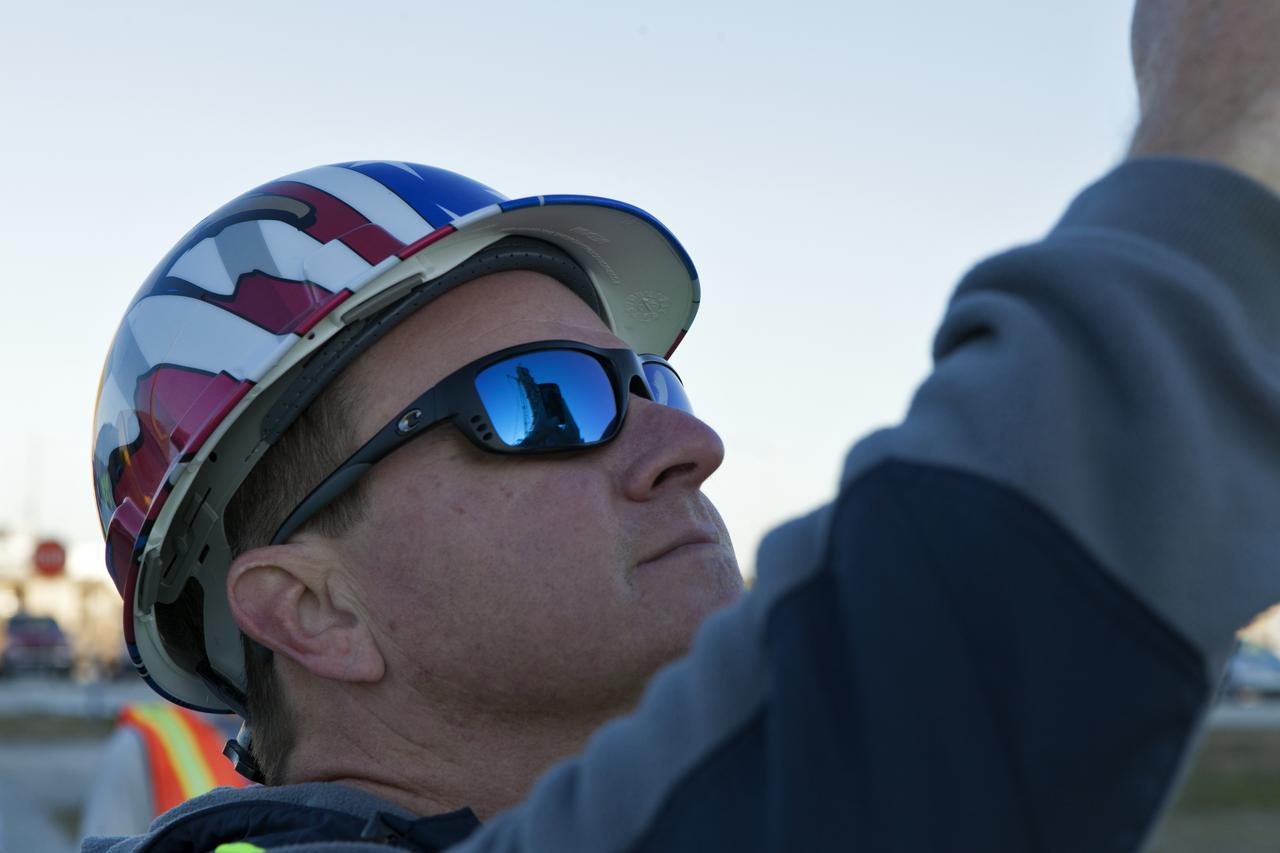The mobile launcher (ML) is reflected in the sunglasses of a construction worker with JP Donovan at NASA's Kennedy Space Center in Florida. A crane is lifting the Interim Cryogenic Propulsion Stage Umbilical (ICPSU) up for installation on the tower of the ML. The last of the large umbilicals to be installed, the ICPSU will provide super-cooled hydrogen and liquid oxygen to the Space Launch System (SLS) rocket's interim cryogenic propulsion stage, or upper stage, at T-0 for Exploration Mission-1. The umbilical is located at about the 240-foot-level of the mobile launcher and will supply fuel, oxidizer, gaseous helium, hazardous gas leak detection, electrical commodities and environment control systems to the upper stage of the SLS rocket during launch. Exploration Ground Systems is overseeing installation of the umbilicals on the ML.