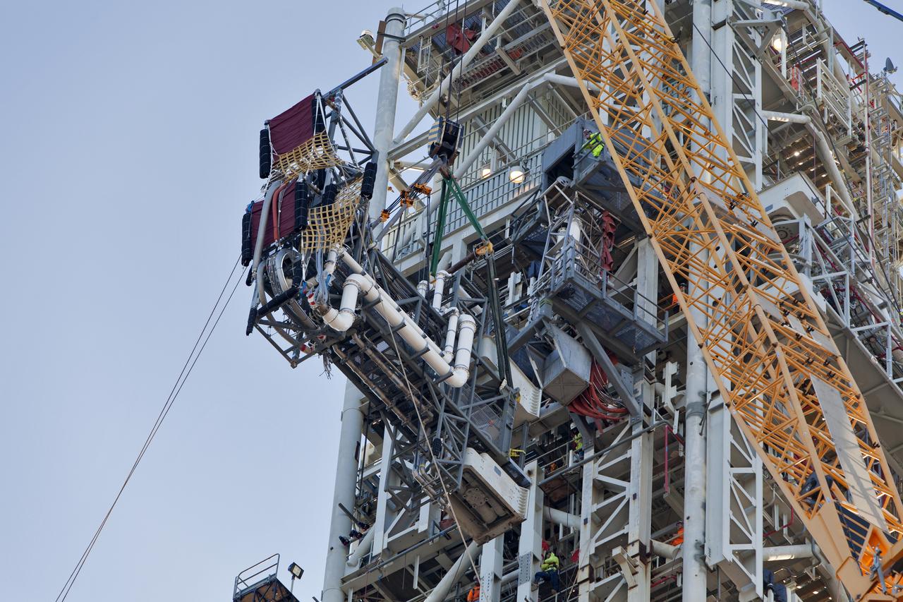 A crane and rigging lines are used to install the Interim Cryogenic Propulsion Stage Umbilical (ICPSU) high up on the mobile launcher (ML) at NASA's Kennedy Space Center in Florida. The last of the large umbilicals to be installed, the ICPSU will provide super-cooled hydrogen and liquid oxygen to the Space Launch System (SLS) rocket's interim cryogenic propulsion stage, or upper stage, at T-0 for Exploration Mission-1. The umbilical is located at about the 240-foot-level of the mobile launcher and will supply fuel, oxidizer, gaseous helium, hazardous gas leak detection, electrical commodities and environment control systems to the upper stage of the SLS rocket during launch. Exploration Ground Systems is overseeing installation of the umbilicals on the ML. 