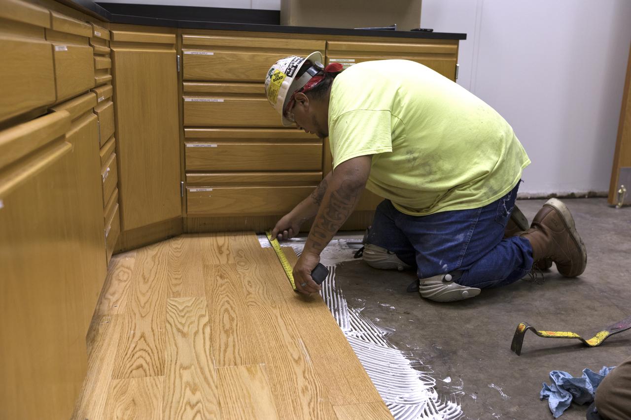Modifications and upgrades are underway inside the Astronaut Crew Quarters in the Neil Armstrong Operations and Checkout Building at NASA's Kennedy Space Center in Florida. A carpenter measures an area for new wood flooring inside the kitchen. The crew quarters are being prepared for the next generation of space explorers. The historic facility housed Apollo and space shuttle astronauts before and after their missions into space.