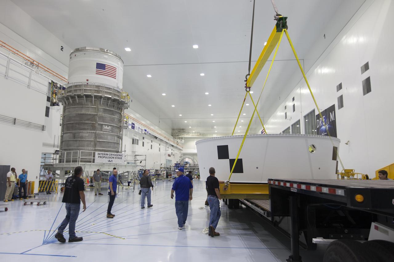 Inside the Space Station Processing Facility (SSPF) high bay at NASA's Kennedy Space Center in Florida, workers assist as a crane lifts the Orion Stage Adapter (OSA) up from the flatbed of a transport truck. The OSA is the second flight-hardware section of the agency's Space Launch System (SLS) rocket to arrive at Kennedy. The OSA will connect the Orion spacecraft to the upper part of the SLS, the interim cryogenic propulsion stage (ICPS). Both the OSA and ICPS, at left, are being stored for processing in the center's SSPF in preparation for Exploration Mission-1, the first uncrewed, integrated launch of the SLS rocket and Orion spacecraft. 