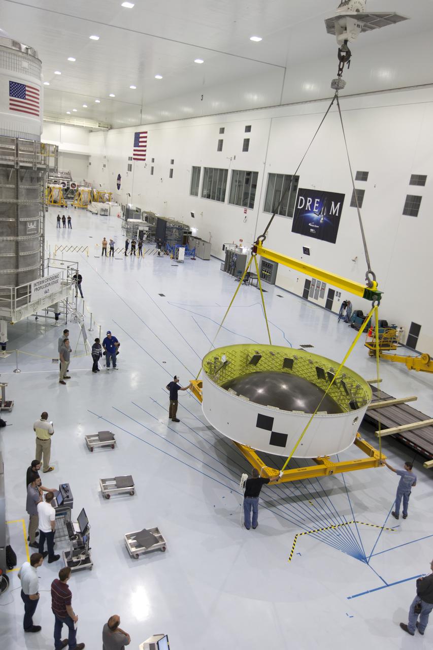 In this view from above in the Space Station Processing Facility (SSPF) high bay at NASA's Kennedy Space Center in Florida, technicians assist as a crane moves the Orion Stage Adapter (OSA) to a work area. The OSA is the second flight-hardware section of NASA's Space Launch System (SLS) rocket to arrive at Kennedy. The OSA will connect the Orion spacecraft to the upper part of the SLS, the interim cryogenic propulsion stage (ICPS). Both the OSA and ICPS, at left, are being stored for processing in the center's SSPF in preparation for Exploration Mission-1, the first uncrewed, integrated launch of the SLS rocket and Orion spacecraft. 