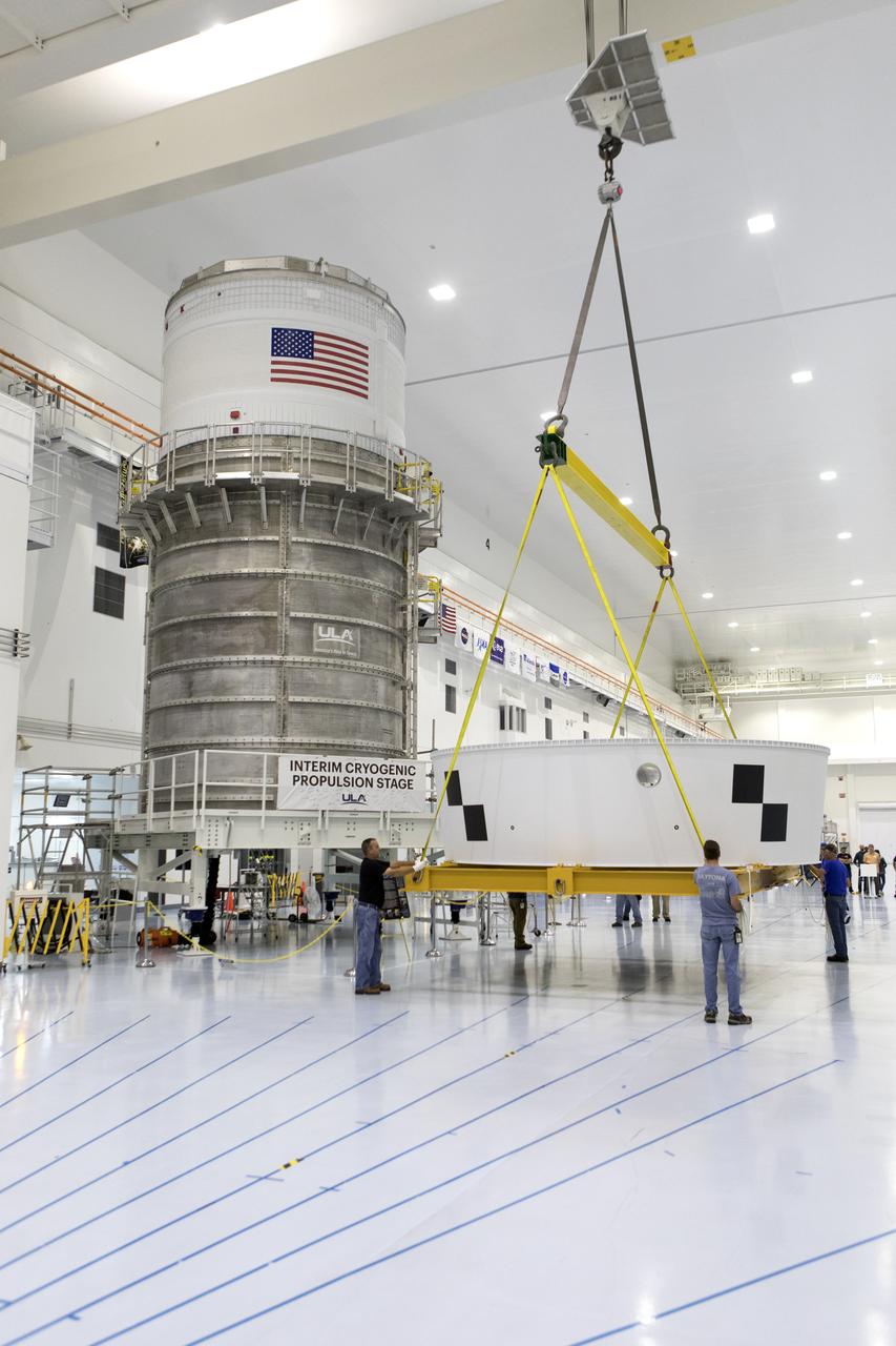 Inside the Space Station Processing Facility (SSPF) high bay at NASA's Kennedy Space Center in Florida, workers assist as a crane moves the Orion Stage Adapter (OSA) to a work area. The OSA is the second flight-hardware section of the agency's Space Launch System (SLS) rocket to arrive at Kennedy. The OSA will connect the Orion spacecraft to the upper part of the SLS, the interim cryogenic propulsion stage (ICPS). Both the OSA and ICPS, at left, are being stored for processing in the center's SSPF in preparation for Exploration Mission-1, the first uncrewed, integrated launch of the SLS rocket and Orion spacecraft.