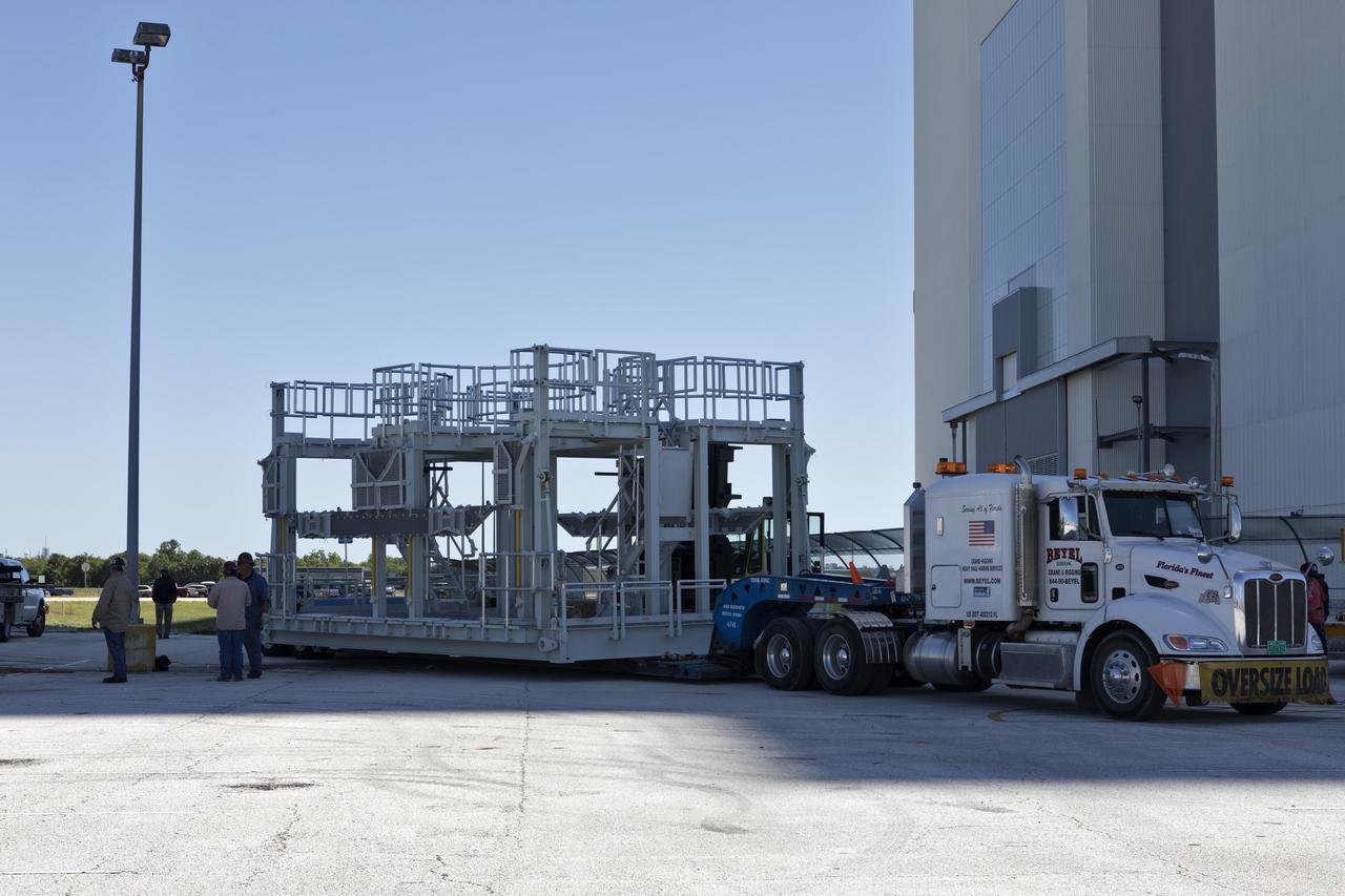 A new service platform for NASA's Space Launch System booster engines, secured on a flatbed truck, has arrived at the Vehicle Assembly Building (VAB) at the agency's Kennedy Space Center in Florida. It was transported from fabricator Met-Con Inc. in Cocoa, Florida. The platform will be stored in the VAB and used for processing and checkout of the engines for the rocket's twin five-segment solid rocket boosters for Exploration Mission-1 (EM-1). During EM-1, an uncrewed Orion spacecraft will launch on the SLS to a stable orbit beyond the Moon and return to Earth for a splashdown in the Pacific Ocean. 