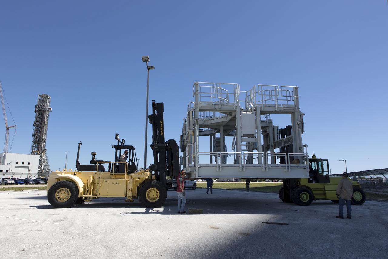 A new service platform for NASA's Space Launch System booster engines has been offloaded from a flatbed truck and is being prepared for the move into the Vehicle Assembly Building (VAB) at the agency's Kennedy Space Center in Florida. The platform was transported from fabricator Met-Con Inc. in Cocoa, Florida. It will be stored in the VAB, and used for processing and checkout of the engines for the rocket's twin five-segment solid rocket boosters for Exploration Mission-1.  EM-1 will launch an uncrewed Orion spacecraft to a stable orbit beyond the Moon and bring it back to Earth for a splashdown in the Pacific Ocean. 