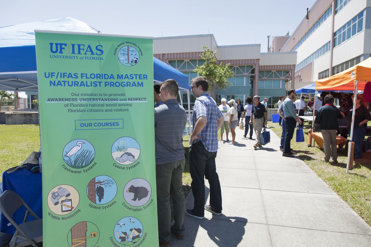 Employees stop by the University of Florida's Institute of Food and Agricultural Sciences booth at Kennedy Space Center’s annual Earth Day celebration. The two-day event featured approximately 50 exhibitors offering information on a variety of topics, including electric vehicles, sustainable lighting, renewable energy, Florida-friendly landscaping tips, Florida’s biking trails and more.