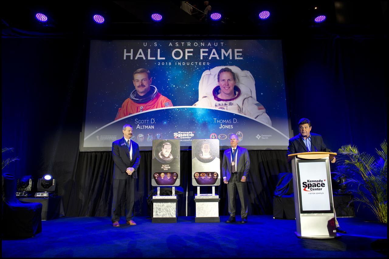 Former astronauts and space explorers Scott D. Altman, at left, and Thomas D. Jones, Ph.D., are inducted into the U.S. Astronaut Hall of Fame Class of 2018 during a ceremony inside the Space Shuttle Atlantis attraction at NASA’s Kennedy Space Center Visitor Complex in Florida. They unveiled their plaques, which will be placed in Hall of Fame at the visitor complex. At far right is Master of Ceremonies, John Zarella, former CNN space correspondent. Inductees into the Hall of Fame are selected by a committee of Hall of Fame astronauts, former NASA officials, flight directors, historians and journalists. The process is administered by the Astronaut Scholarship Foundation. To be eligible, an astronaut must have made his or her first flight at least 17 years before the induction. Candidates must be a U.S. citizen and a NASA-trained commander, pilot or mission specialist who has orbited the earth at least once. Including Altman and Jones, 97 astronauts have been inducted into the AHOF.
