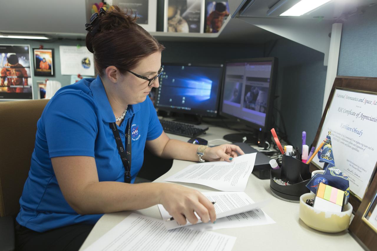 Kathleen O'Brady reviews documents in her office at NASA’s Kennedy Space Center in Florida. As a certification systems engineer in the Commercial Crew Program’s (CCP's) Systems Engineering and Integration Office, she is responsible for defining an integrated plan for certification which is being executed by the agency's CCP partners Boeing and SpaceX. The two companies are developing spacecraft to fly NASA astronauts to the International Space Station and return them safely home.