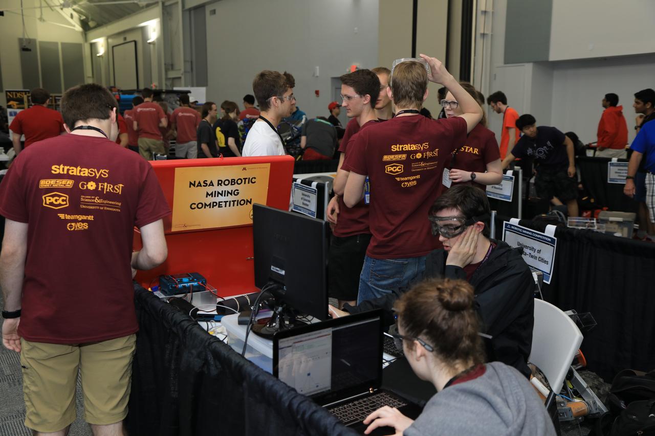 On the first day of NASA's 9th Robotic Mining Competition, set-up day on May 14, team members from the University of Minnesota-Twin Cities work on their robot miner in the RobotPits in the Educator Resource Center at Kennedy Space Center Visitor Complex in Florida. More than 40 student teams from colleges and universities around the U.S. will use their mining robots to dig in a supersized sandbox filled with BP-1, or simulated Lunar soil, gravel and rocks, and participate in other competition requirements. The Robotic Mining Competition is a NASA Human Exploration and Operations Mission Directorate project designed to encourage students in science, technology, engineering and math, or STEM fields. The project provides a competitive environment to foster innovative ideas and solutions that could be used on NASA's deep space missions.