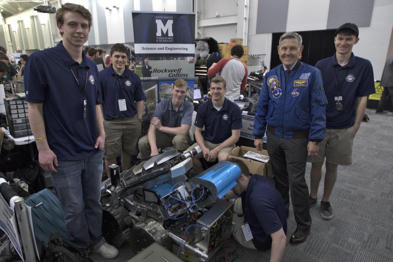 On the second day of NASA's 9th Robotic Mining Competition, May 15, team members from the South Dakota School of Mines & Engineering work on their robot miner in the RobotPits in the Educator Resource Center at Kennedy Space Center Visitor Complex in Florida. Second from right is Kennedy Space Center Director Bob Cabana. More than 40 student teams from colleges and universities around the U.S. will use their mining robots to dig in a supersized sandbox filled with BP-1, or simulated Lunar soil, gravel and rocks, and participate in other competition requirements. The Robotic Mining Competition is a NASA Human Exploration and Operations Mission Directorate project designed to encourage students in science, technology, engineering and math, or STEM fields. The project provides a competitive environment to foster innovative ideas and solutions that could be used on NASA's deep space missions.