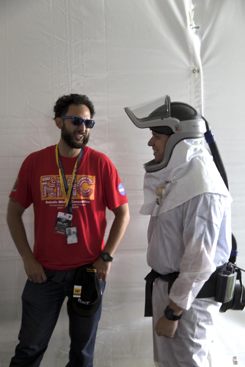 A volunteer talks with a mining judge near the mining arena on the third day of NASA's 9th Robotic Mining Competition, May 16, at NASA's Kennedy Space Center Visitor Complex in Florida. More than 40 student teams from colleges and universities around the U.S. will use their mining robots to dig in a supersized sandbox filled with BP-1, or simulated Lunar soil, gravel and rocks, and participate in other competition requirements. The Robotic Mining Competition is a NASA Human Exploration and Operations Mission Directorate project designed to encourage students in science, technology, engineering and math, or STEM fields. The project provides a competitive environment to foster innovative ideas and solutions that could be used on NASA's deep space missions.