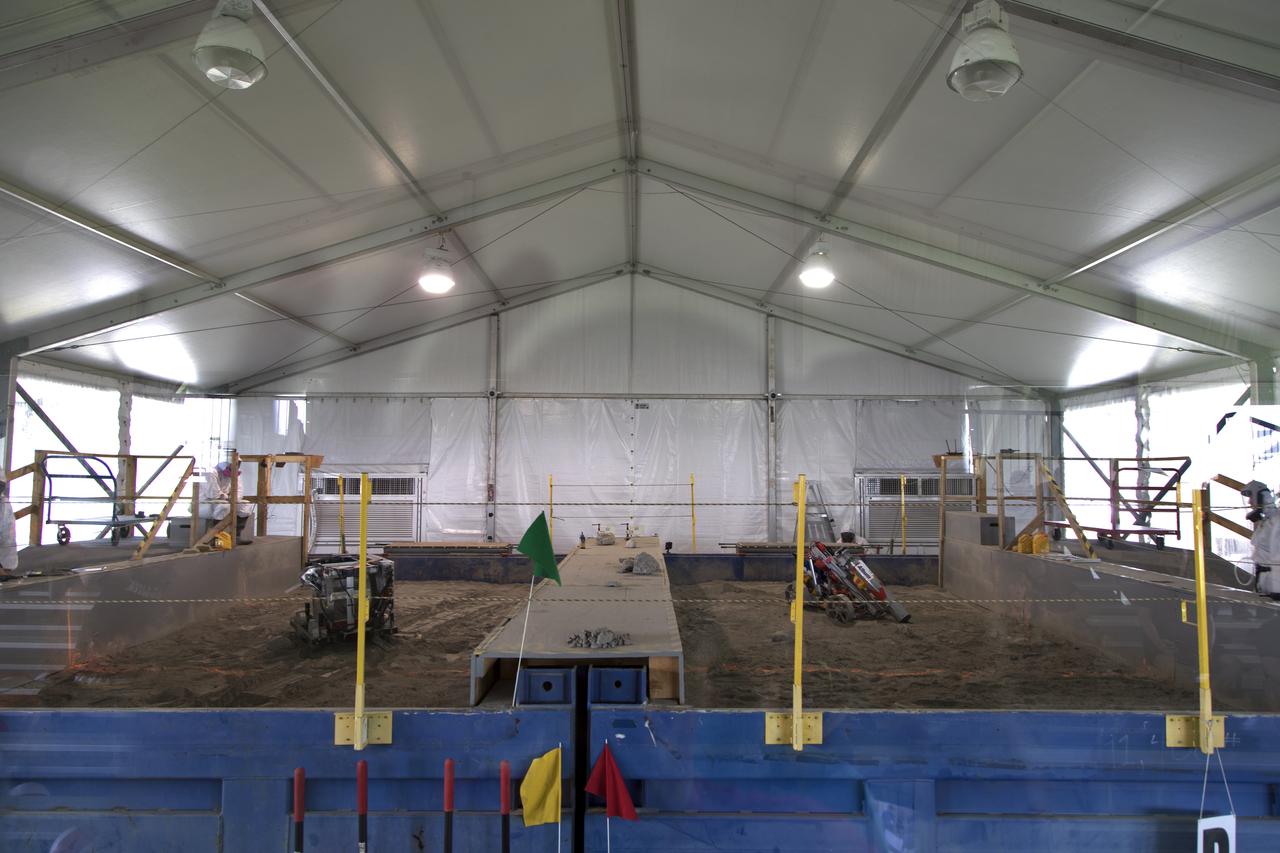 On the third day of NASA's 9th Robotic Mining Competition, May 16, two robot miners dig in the dirt in the mining arena at NASA's Kennedy Space Center Visitor Complex in Florida. More than 40 student teams from colleges and universities around the U.S. will use their mining robots to dig in a supersized sandbox filled with BP-1, or simulated Lunar soil, gravel and rocks, and participate in other competition requirements. The Robotic Mining Competition is a NASA Human Exploration and Operations Mission Directorate project designed to encourage students in science, technology, engineering and math, or STEM fields. The project provides a competitive environment to foster innovative ideas and solutions that could be used on NASA's deep space missions.