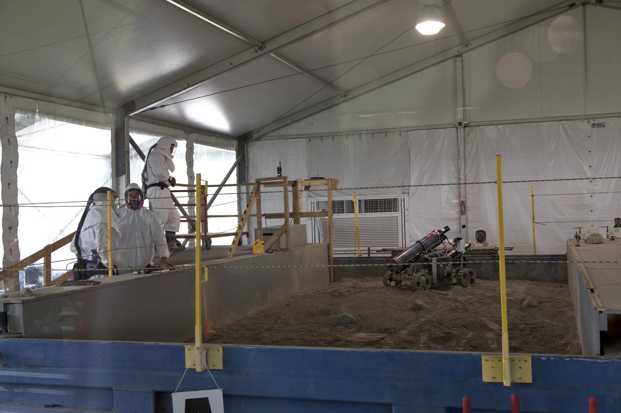 On the third day of NASA's 9th Robotic Mining Competition, May 16, judges watch as a robot miner digs in the dirt in the mining arena at NASA's Kennedy Space Center Visitor Complex in Florida. More than 40 student teams from colleges and universities around the U.S. will use their mining robots to dig in a supersized sandbox filled with BP-1, or simulated Lunar soil, gravel and rocks, and participate in other competition requirements. The Robotic Mining Competition is a NASA Human Exploration and Operations Mission Directorate project designed to encourage students in science, technology, engineering and math, or STEM fields. The project provides a competitive environment to foster innovative ideas and solutions that could be used on NASA's deep space missions.