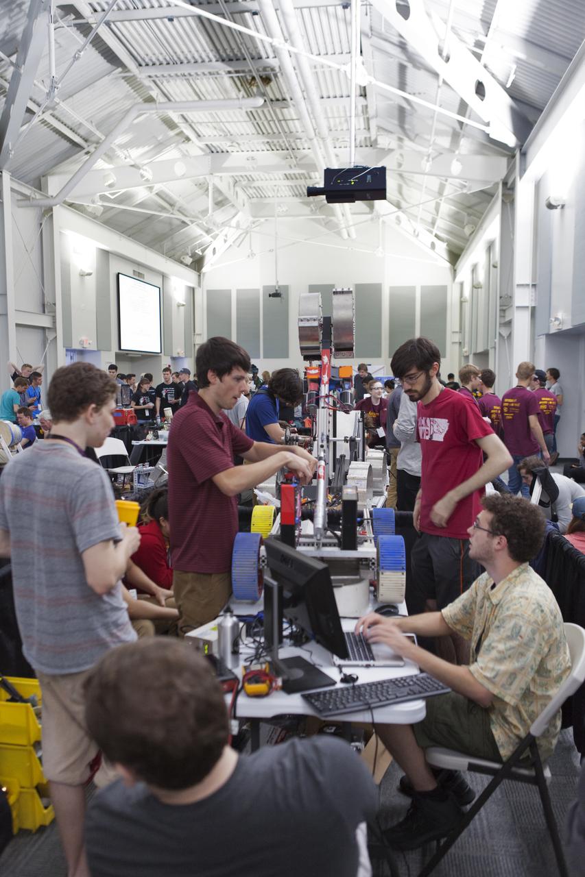 Team members from the University of Arkansas make adjustments to their robot miner for its turn in the mining arena on the fourth day of NASA's 9th Robotic Mining Competition, May 17, at NASA's Kennedy Space Center Visitor Complex in Florida. They are in the RobotPits inside the Educator Resource Center. More than 40 student teams from colleges and universities around the U.S. are using their mining robots to dig in a supersized sandbox filled with BP-1, or simulated Lunar soil, gravel and rocks, and participate in other competition requirements. The Robotic Mining Competition is a NASA Human Exploration and Operations Mission Directorate project designed to encourage students in science, technology, engineering and math, or STEM fields. The project provides a competitive environment to foster innovative ideas and solutions that could be used on NASA's deep space missions.