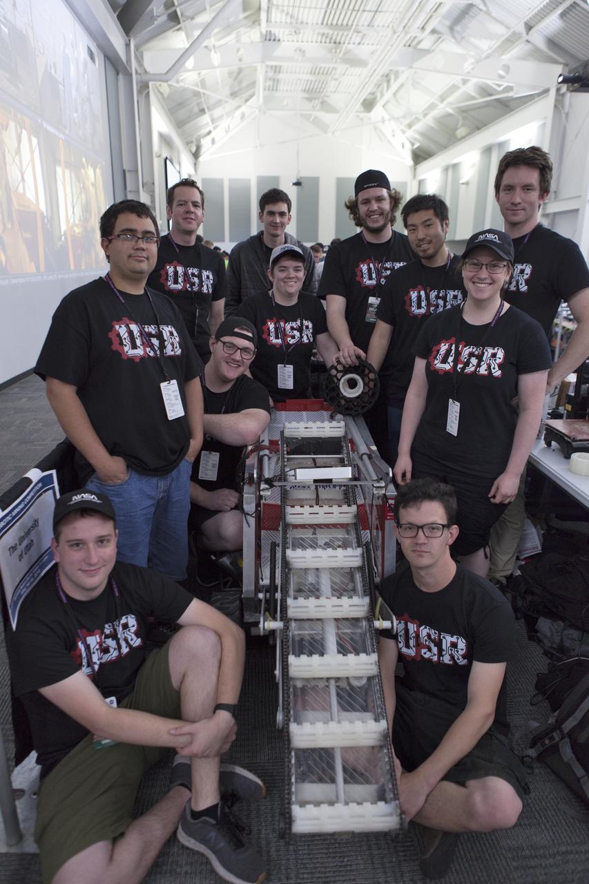 Team members from The University of Utah pause with their robot miner in the RobotPits on the fourth day of NASA's 9th Robotic Mining Competition, May 17, at NASA's Kennedy Space Center Visitor Complex in Florida. More than 40 student teams from colleges and universities around the U.S. are using their mining robots to dig in a supersized sandbox filled with BP-1, or simulated Lunar soil, gravel and rocks, and participate in other competition requirements. The Robotic Mining Competition is a NASA Human Exploration and Operations Mission Directorate project designed to encourage students in science, technology, engineering and math, or STEM fields. The project provides a competitive environment to foster innovative ideas and solutions that could be used on NASA's deep space missions.