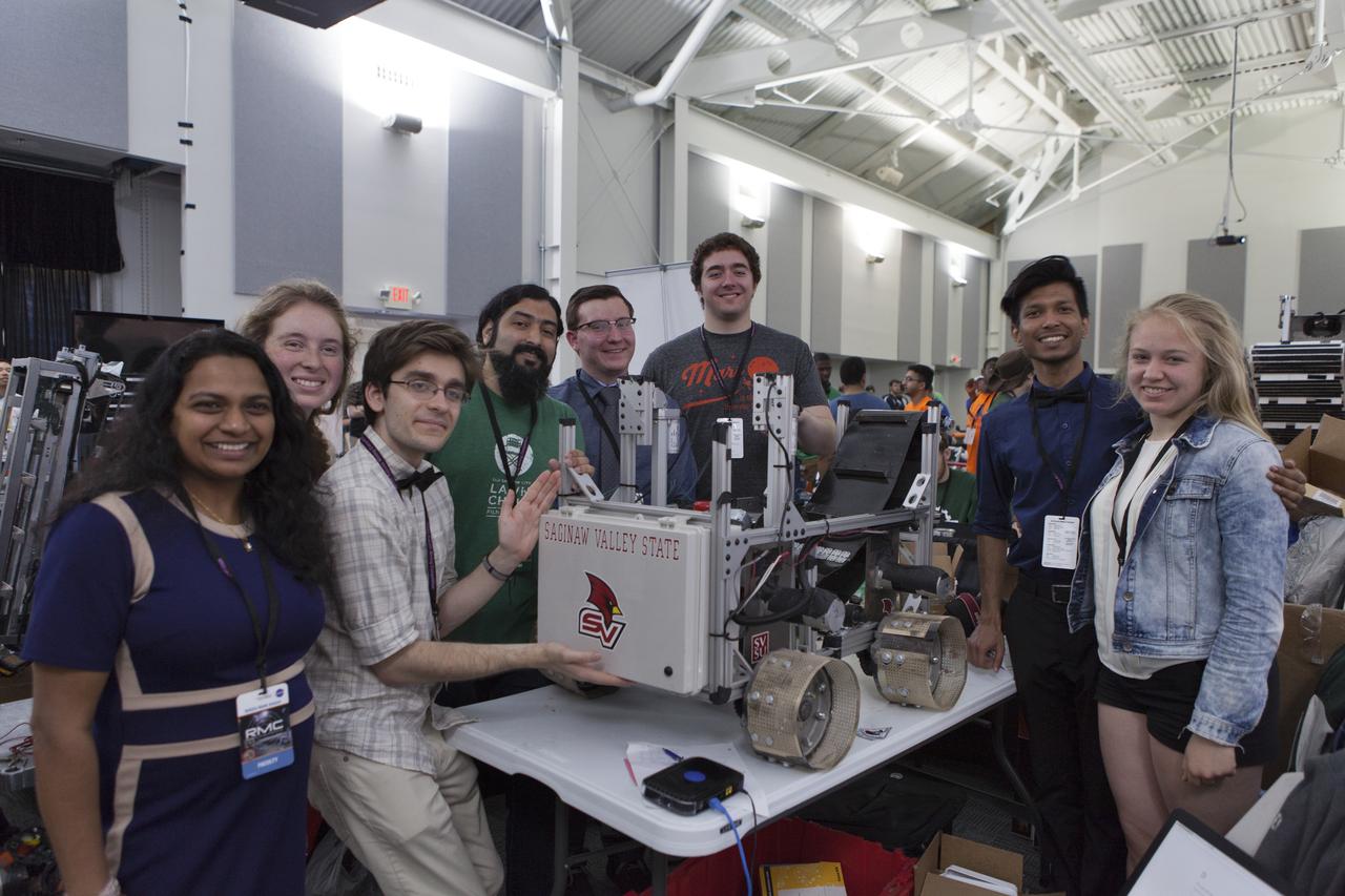 First-time participants from Saginaw Valley State University pause with their robot miner in the RobotPits on the fourth day of NASA's 9th Robotic Mining Competition, May 17, at NASA's Kennedy Space Center Visitor Complex in Florida. More than 40 student teams from colleges and universities around the U.S. are using their mining robots to dig in a supersized sandbox filled with BP-1, or simulated Lunar soil, gravel and rocks, and participate in other competition requirements. The Robotic Mining Competition is a NASA Human Exploration and Operations Mission Directorate project designed to encourage students in science, technology, engineering and math, or STEM fields. The project provides a competitive environment to foster innovative ideas and solutions that could be used on NASA's deep space missions. 