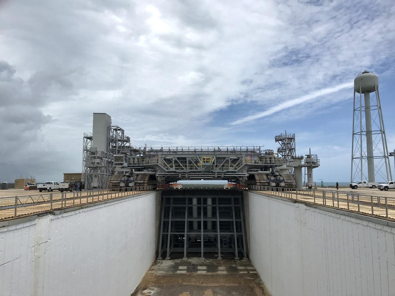 Crawler-transporter 2 (CT-2) arrives on the surface of Launch Pad 39B for a fit check on May 22, 2018, at NASA's Kennedy Space Center in Florida. The test drive to the pad confirms that all of the recent modifications to CT-2 and Pad 39B are operational to support the launch of the agency's Space Launch System rocket and Orion spacecraft on Exploration Mission-1. In view is the south side of the flame trench and the south side of the recently installed new main flame deflector. Exploration Ground Systems managed the modifications and upgrades to CT-2 and Pad 39B to prepare for EM-1 and deep space exploration missions.
