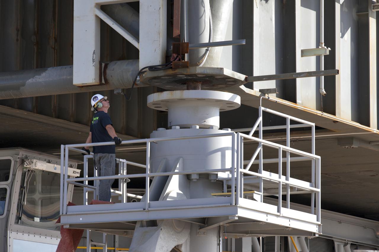A construction worker monitors the progress as crawler-transporter 2 (CT-2) lifts the mobile launcher up a few inches from its support posts June 1, 2018, at NASA's Kennedy Space Center in Florida. Three lifts were performed to practice lifting procedures, validate interface locations, confirm the weight of the mobile launcher, and develop a baseline for modal analysis. The mobile launcher is equipped with a number of lines, called umbilicals, which will connect to NASA's Space Launch System (SLS) and Orion. The lift helped to test the capability of the upgraded CT-2 to handle the weight of the mobile launcher. Exploration Ground Systems is preparing the ground systems necessary to support the SLS and Orion spacecraft for Exploration Mission-1 and deep space missions.