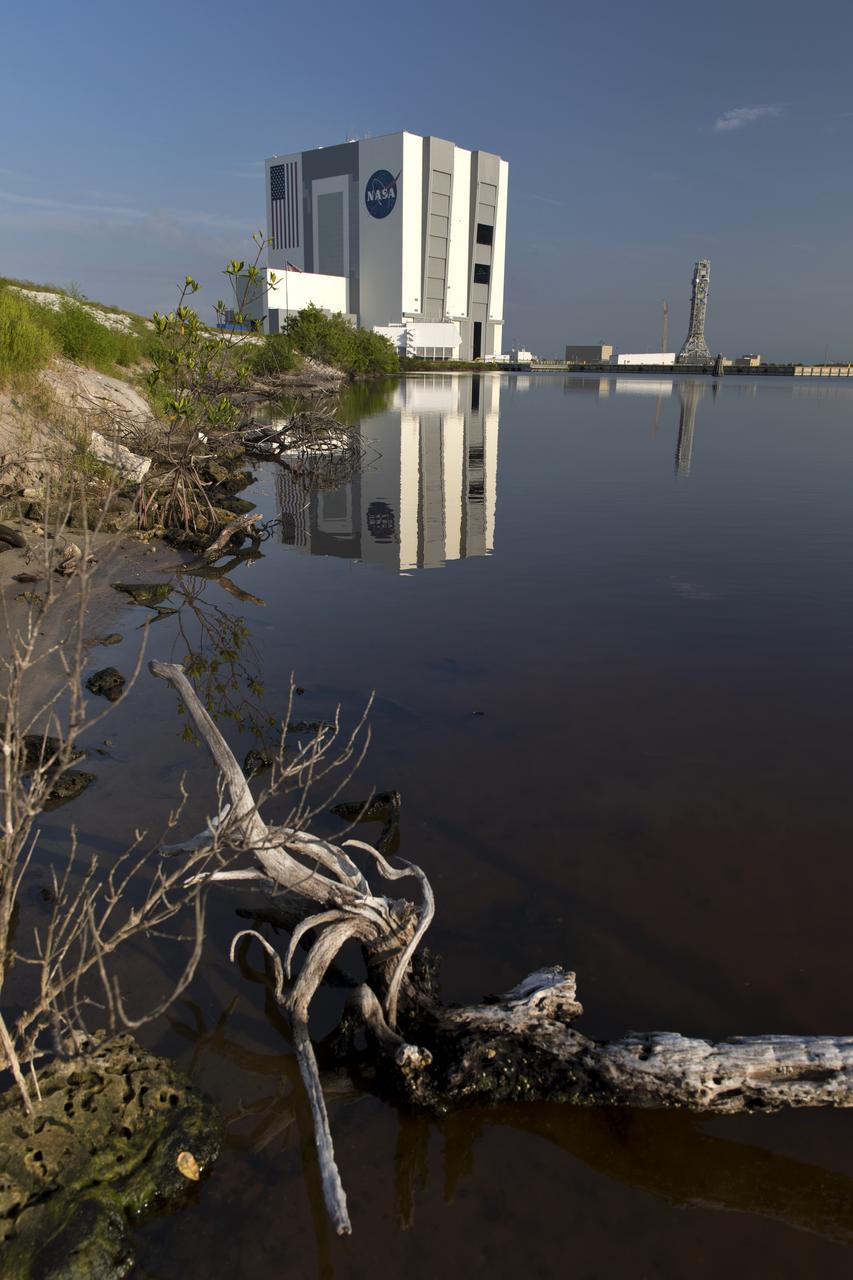 The iconic Vehicle Assembly Building (VAB) casts a reflection in a surrounding waterway at NASA's Kennedy Space Center in Florida. In view are the south and east sides of the building. Ten levels of new work platforms have been installed in VAB High Bay 3. They will surround and provide access for service and processing of NASA's Space Launch System (SLS) rocket and Orion spacecraft. Exploration Ground Systems oversaw the upgrades and installation of the new work platforms to support the launch of the SLS and Orion on Exploration Mission-1 and deep space missions.