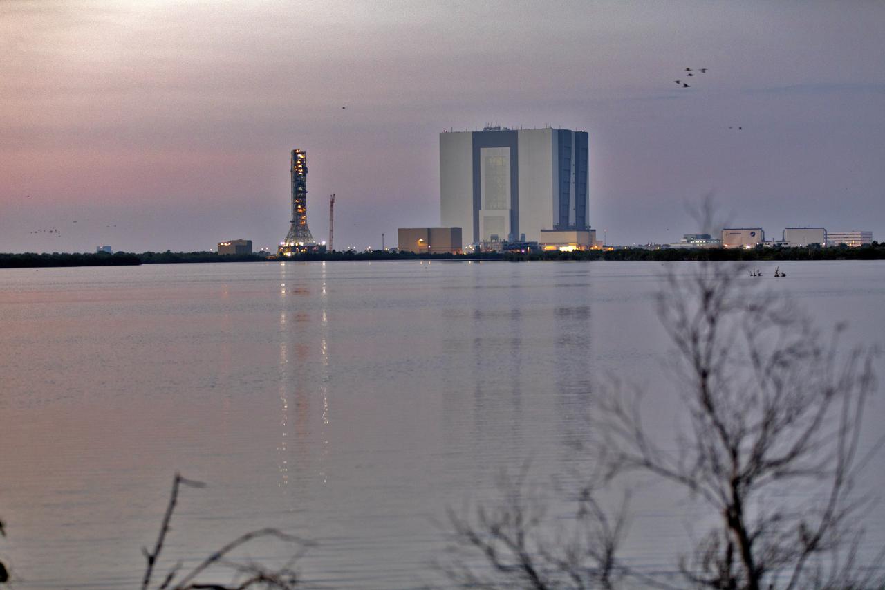 An early morning view of the iconic Vehicle Assembly Building, at right, and mobile launcher at NASA's Kennedy Space Center in Florida, on June 21, from the Saturn V center at nearby Kennedy Space Center Visitor Complex. Exploration Ground Systems is preparing both to support processing and launch of the agency's Space Launch System rocket and Orion spacecraft on Exploration Mission-1 and deep space missions.