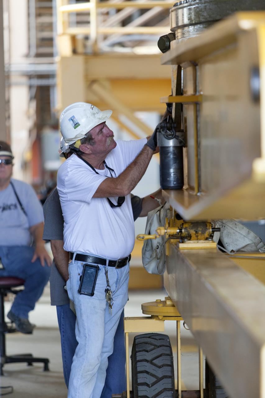 A Jacobs technician, on the Test and Operations Support Contract, checks bolt fittings during practice crane operations with an inert booster rocket segment in the Rotation, Processing and Surge Facility on June 22, 2018, at NASA's Kennedy Space Center in Florida. Dual cranes will be used to move the segment from vertical to horizontal, a maneuver known as a "breakover rotation." As part of routine processing operations for the agency's Space Launch System (SLS) rocket, the RPSF team will receive all of the solid rocket fuel segments for inspection and preparation prior to transporting them to the Vehicle Assembly Building for stacking on the mobile launcher. Many pathfinding operations are being done to prepare for launch of the SLS and Orion spacecraft on Exploration Mission-1 and deep space missions.