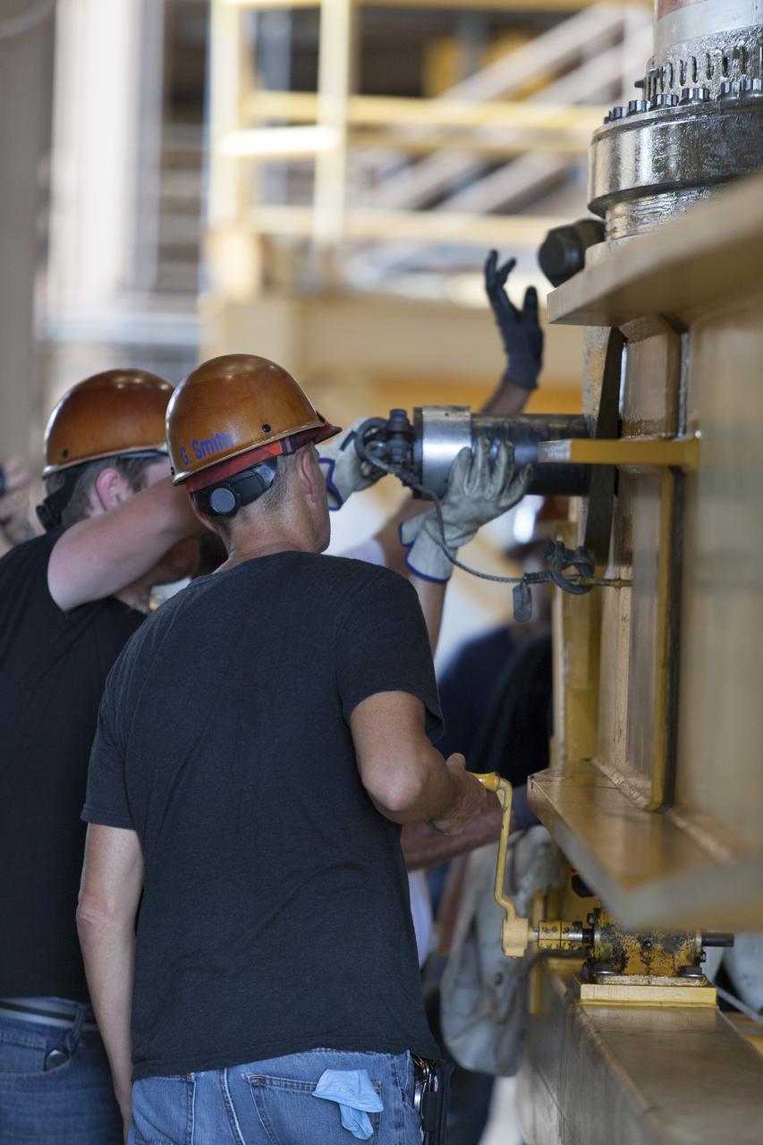 Jacobs technicians, on the Test and Operations Support Contract, check bolt fittings as they practice crane operations with an inert booster rocket segment in the Rotation, Processing and Surge Facility on June 22, 2018, at NASA's Kennedy Space Center in Florida. Dual cranes are being used to move the segment from vertical to horizontal, a maneuver known as a "breakover rotation." As part of routine processing operations for the agency's Space Launch System (SS) rocket, the RPSF team will receive all of the solid rocket fuel segments for inspection and preparation prior to transporting them to the Vehicle Assembly Building for stacking on the mobile launcher. Many pathfinding operations are being done to prepare for launch of the SLS and Orion spacecraft on Exploration Mission-1 and deep space missions.